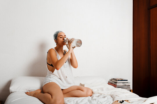 Portrait of androgyne model drinking water at bedroom