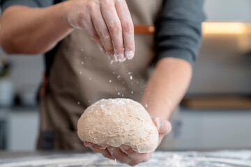 Man sprinkling flour on a mass of bread
