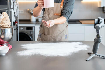 Man recording while spreading flour on a kitchen