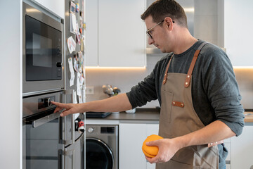 Adult man using the oven in the kitchen