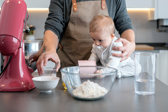 Father with a baby in a table with cooking utensils and ingredients.