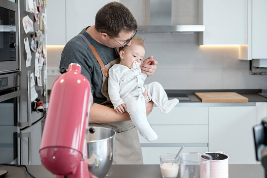 Father kissing and holding baby in a kitchen