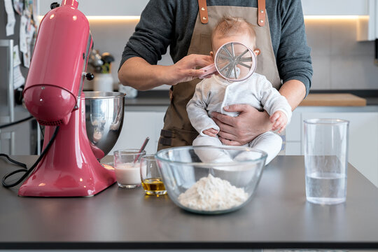 Father and baby playing with kitchen utensils