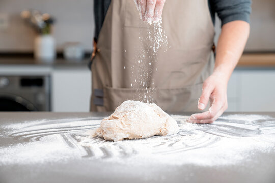 Man spreading flour on top of bread dough