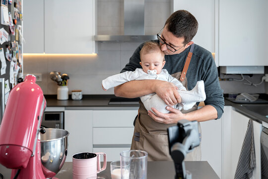 Man kissing a baby while embracing him in a kitchen