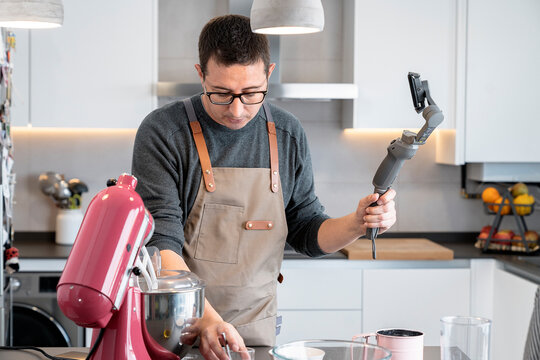 Man recording himself with mobile phone while cooking