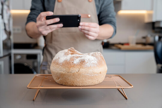 Man taking a photo with a phone of a bread at home