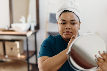 Black woman applying facial cream during beauty routine at home