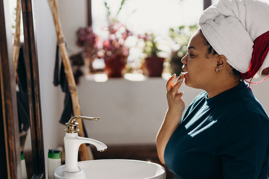 Pretty Black Woman Applying Lip Balm In Bathroom