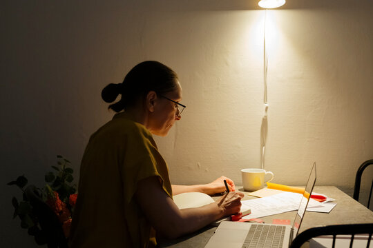 Mature woman working under dim illumination