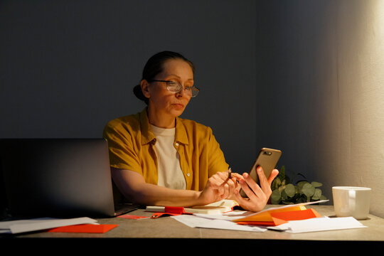 Middle aged woman browsing smartphone during work