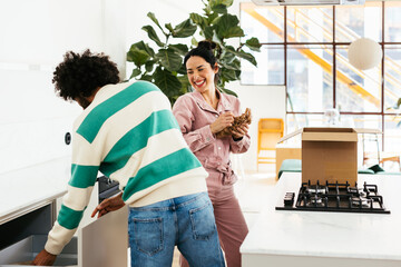 Cheerful diverse couple unpacking belongings in kitchen