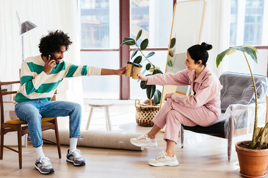 Diverse couple clinking takeaway cups during relocation