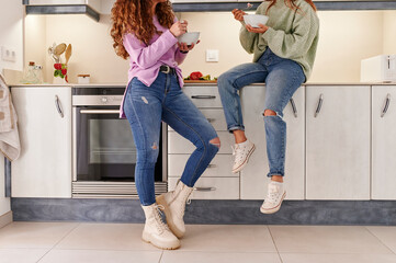 Two female friends eating in their kitchen