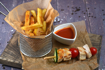 french fries with tomato sauce ketchup beer snack on dark wooden table closeup view with meat kebabs