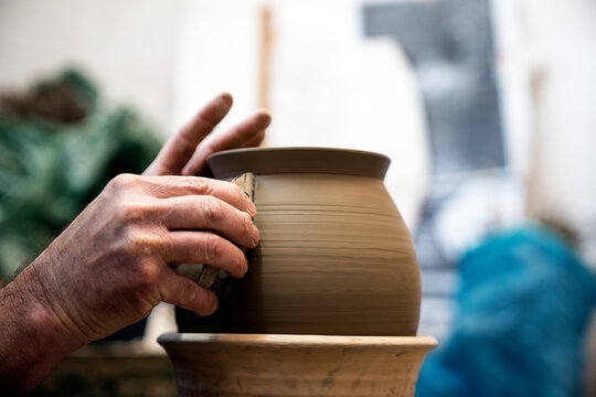 Man polishing a ceramic vessel with a metal tool