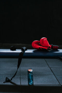Boxing gloves and bandages on the bench and water bottle in a sports club.