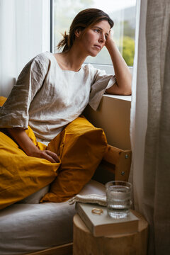 Sad woman sitting on bed in morning