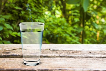Water flows into a glass placed on a wooden desk.