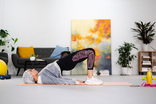 Islamic sportswoman doing hip bridge at home