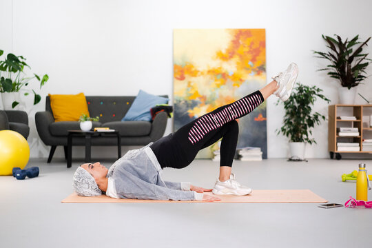 Islamic sportswoman doing hip bridge at home