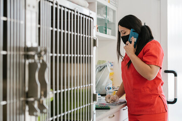 A uniformed veterinarian making a phone call while taking notes in a notebook