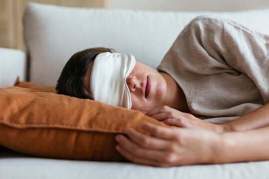 Woman in sleeping mask relaxing on sofa