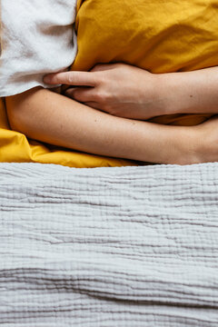 Crop tender woman lying on bed under blanket