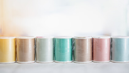 The pastel color embroidery thread spool using in garment industry, row of multicolored yarn rolls, sewing material selling in the market