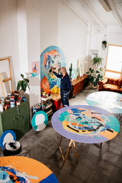 top view of an Artist painting large-format round works in his studio