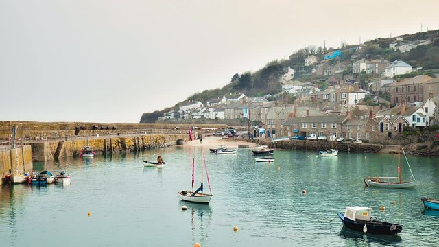Harbour with many boats and coastline houses in a small village in Britain. Mousehole Harbour, Penzance, Cornwall, England in 4K.