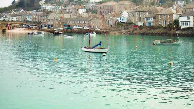 Harbour with many boats and coastline houses in a small village in Britain. Mousehole Harbour, Penzance, Cornwall, England in 4K.