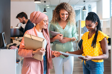 Smiling multiracial colleagues walking in corridor of contemporary office
