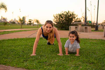 madre e hija haciendo flexiones de brazos en un parque al aire libre  - obrazy, fototapety, plakaty