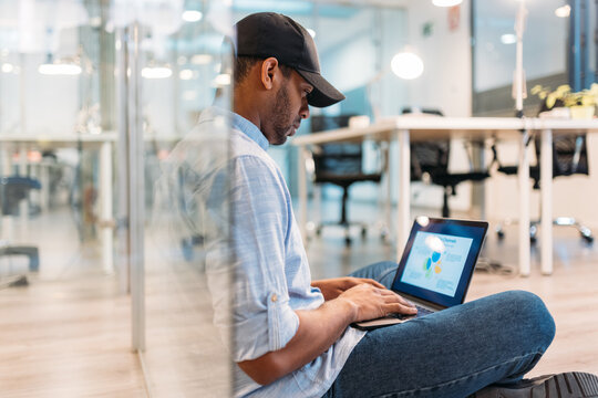 Attentive black analyst studying diagrams on laptop screen in office