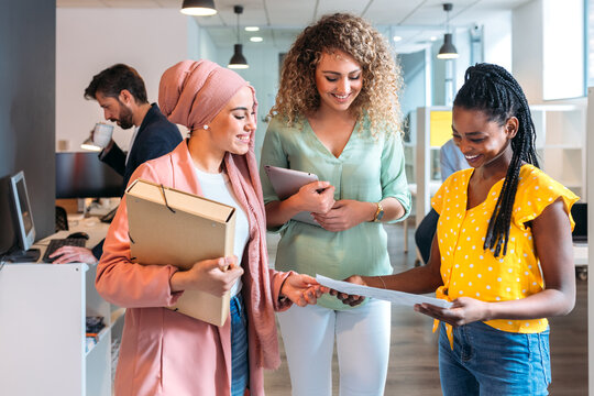 Smiling multiracial colleagues walking in corridor of contemporary office