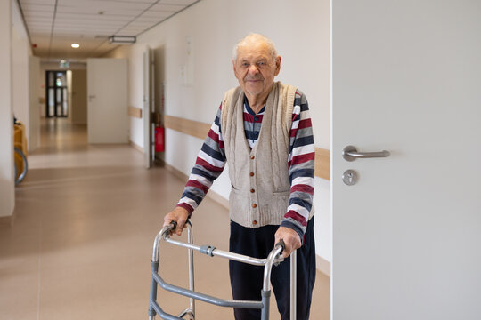 Smiling Senior Man With Walker At Corridor