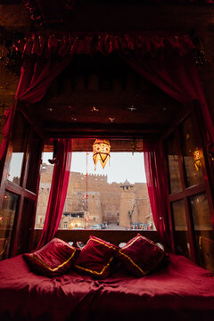 Red cushions line a window seat looking out on an orange fort