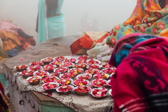Small trays of flowers and candles sit for sale by street vendor
