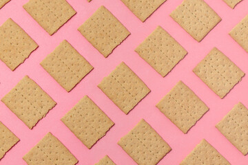 Squares of graham crackers on a pink background. Pattern. Top view, flat lay