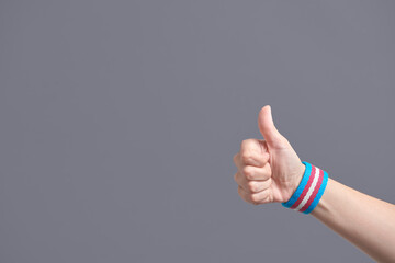Young hand with a transgender flag bracelet with the thumb up