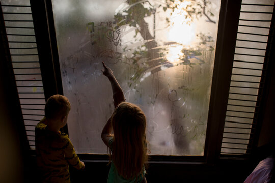 Two Children drawing on steamy windows