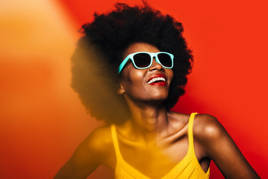 Beautiful Afro Woman posing over yellow background with blue sunglasses