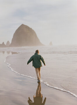 young boy runs in the ocean on the chilly coastal beach