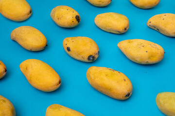 Mango manila maduro acomodado en patrones sobre un fondo color azul.