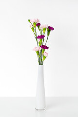 Bouquet of pink flowers at white shelf. Modern interior details.
