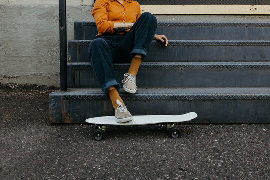 Girl resting on stairs with skateboard