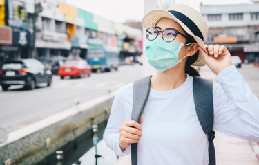 Asian woman smiling behind the mask while travel during the COVID-19 Pandemic.