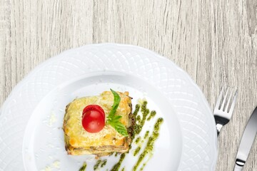 Tasty hot lasagna dish with tomato sauce and cheese served with tomatoes on a plate