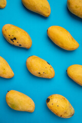 Mango manila maduro acomodado en patrones sobre un fondo color azul.